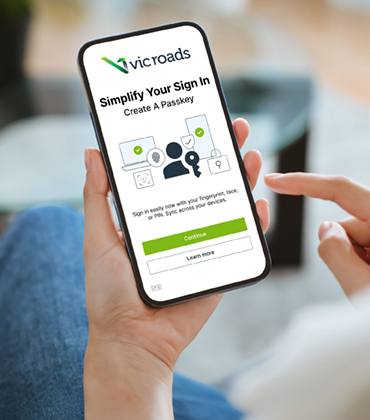 A hand holding a smartphone with the login screen showing with passkeys